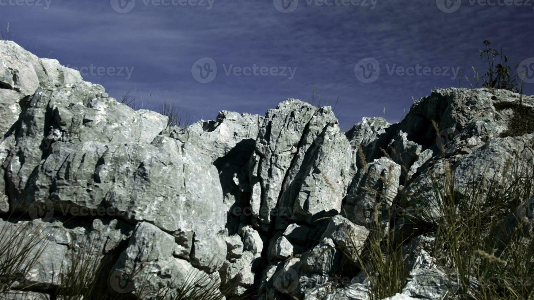 skön sten klippor. kreativ. stor berg intervall stående ovan en blå solig himmel Nästa till lång vass . foto