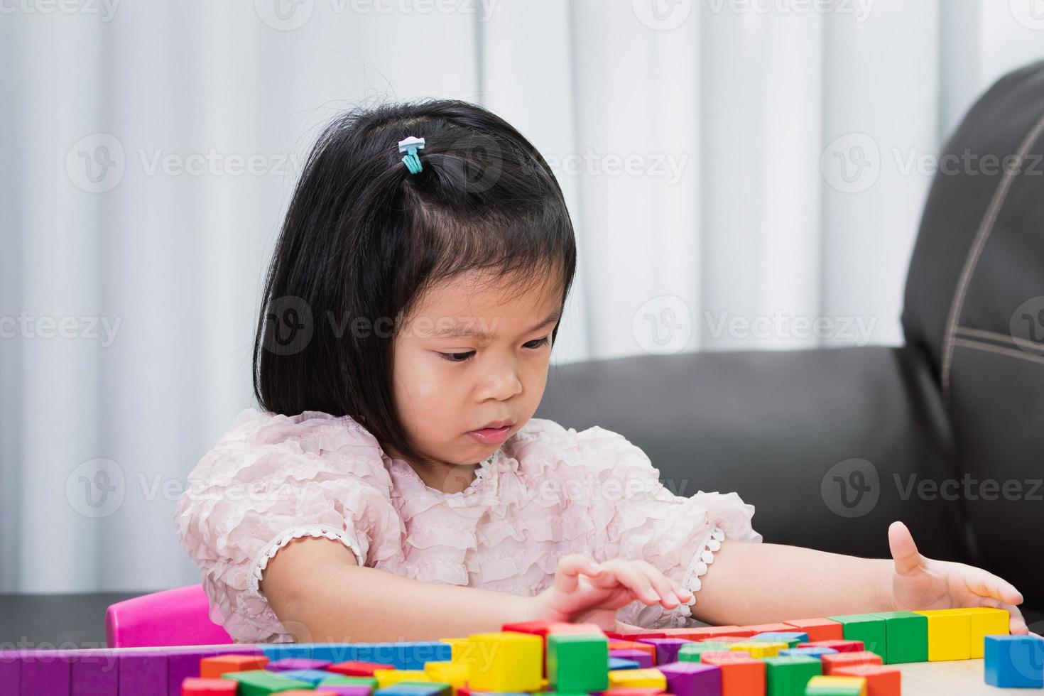 porträtt av ett barn som spenderar sin fritid med att göra aktivitet i huset. barn har roligt att leka med leksaker av träkub. foto