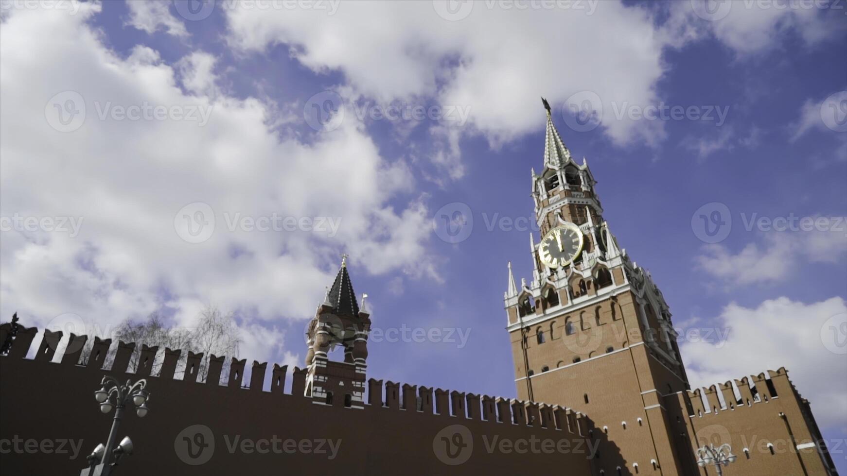 röd kreml fästning och spasskaya torn på bakgrund av blå himmel. handling. topp av röd fästning vägg och kreml klocka torn foto