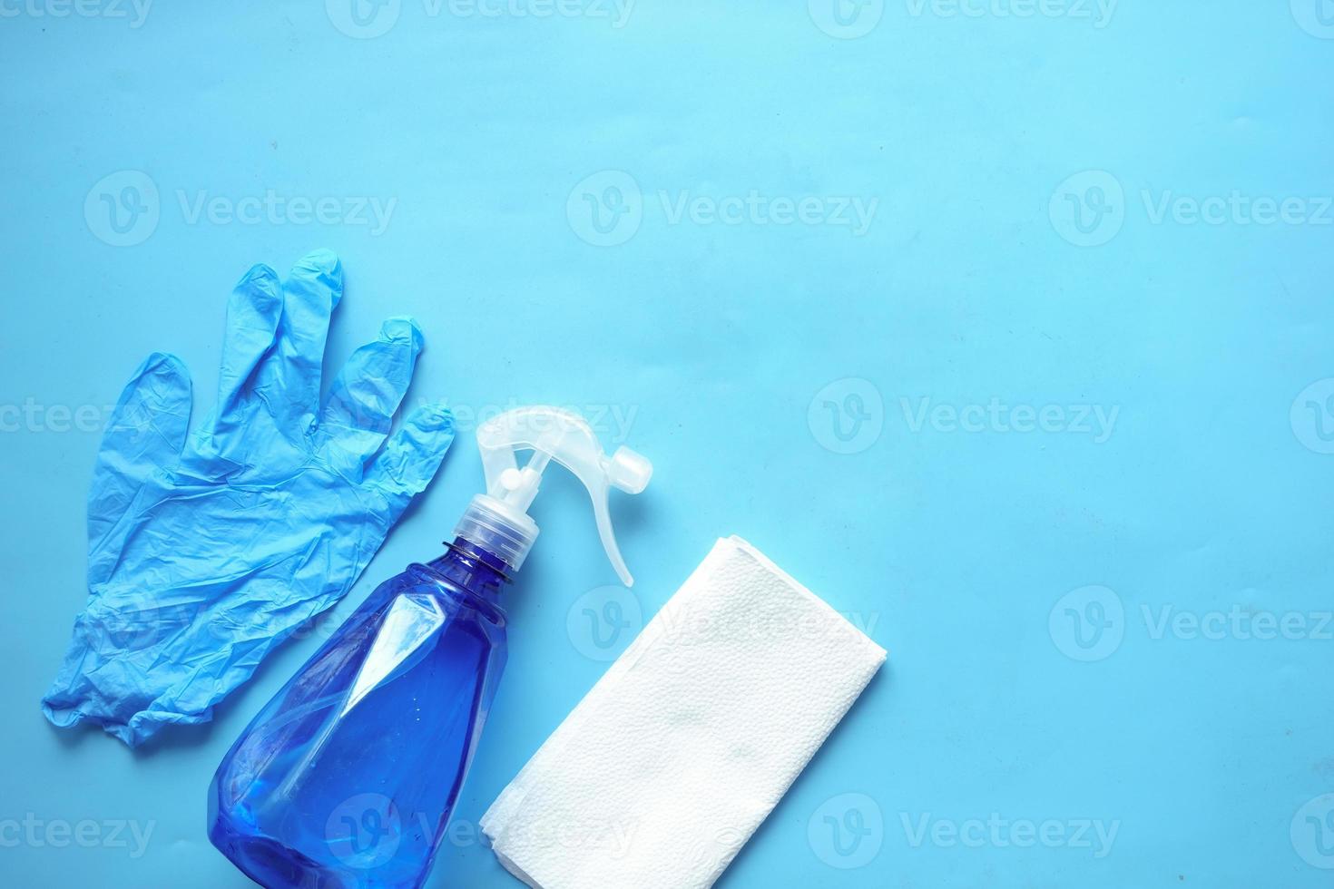 rengöringspapper, flaska och handskar på blått foto