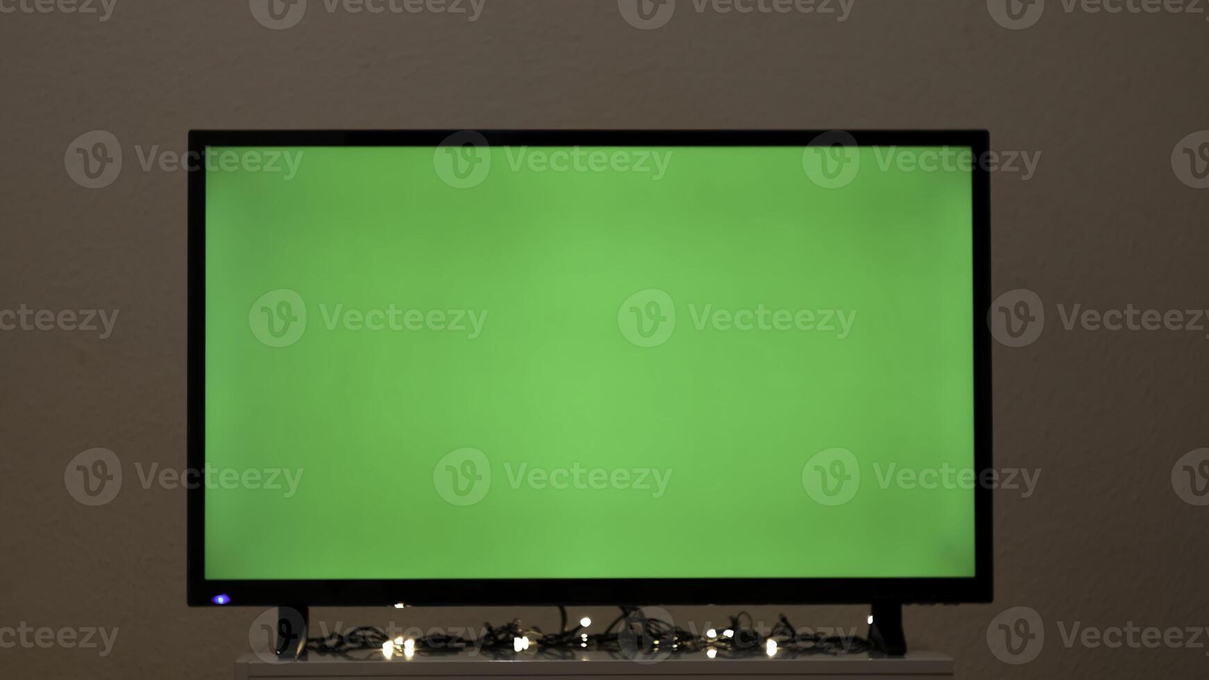 grön TV skärm med blinkande krans. begrepp. krans blinkar på bakgrund av grön TV i rum. grön skärm TV i tömma rum med festlig atmosfär foto