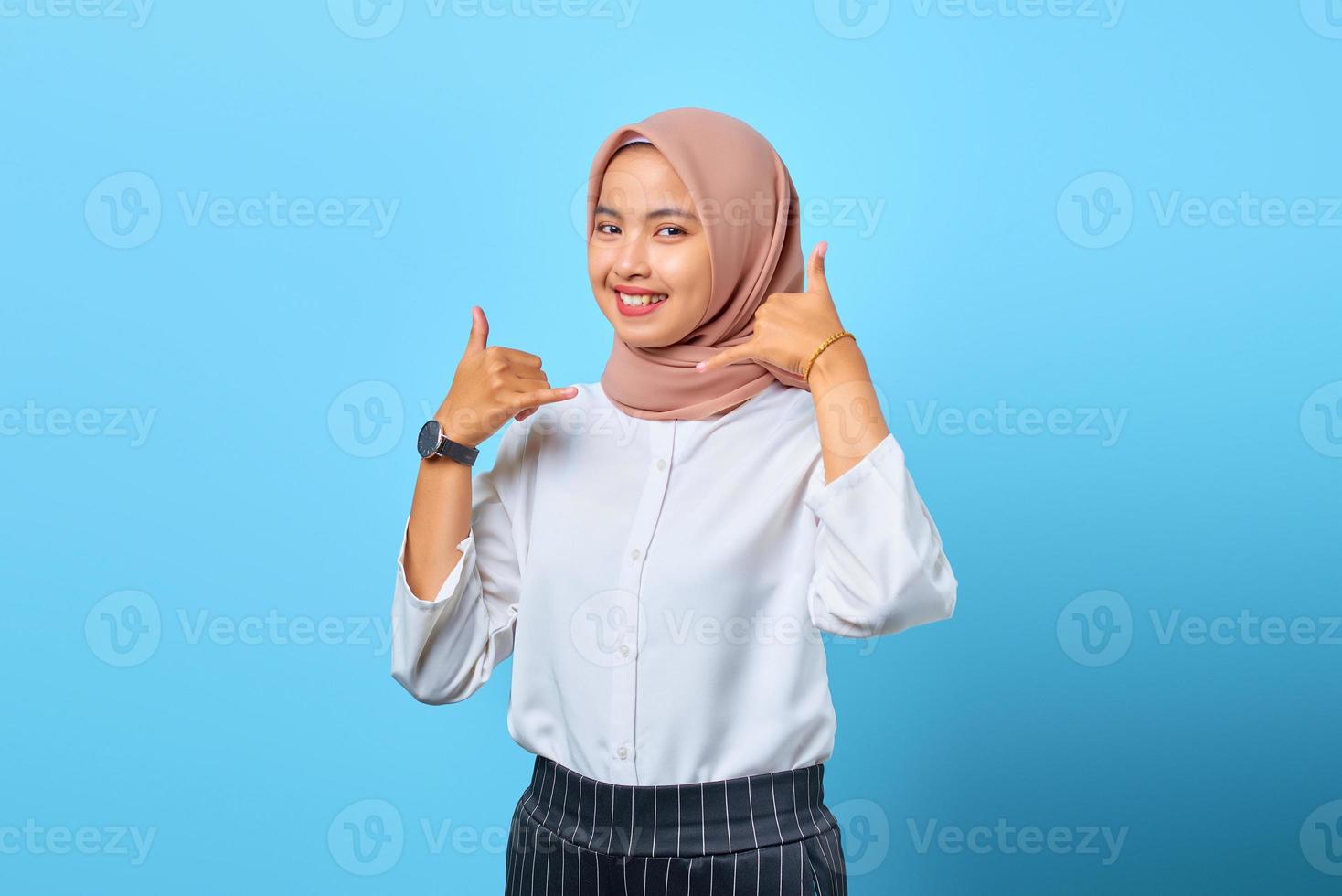 porträtt av attraktiv glad ung asiatisk kvinna gör telefon gest med handen foto