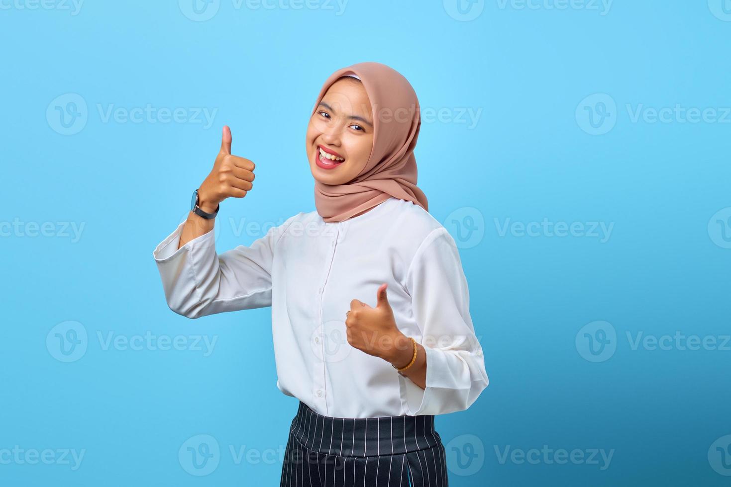 porträtt av upphetsad glad ung asiatisk kvinna som visar tummen upp eller godkännande tecken foto