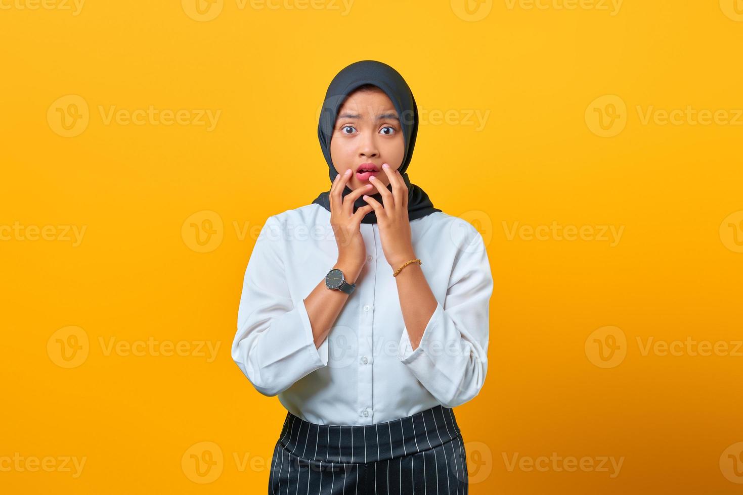 orolig orolig ung asiatisk kvinna rädd för något isolerat över gul bakgrund foto