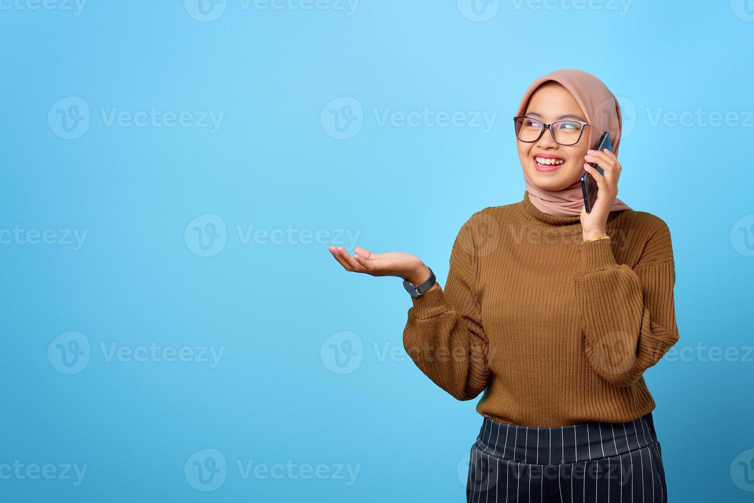 porträtt av glad vacker asiatisk kvinna som pratar i mobiltelefon på blå bakgrund foto