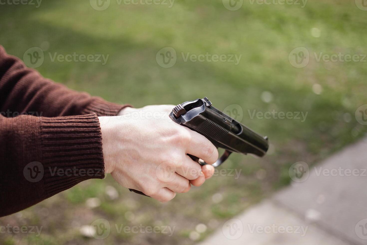 en man kostnader en pistol mot en grön gräs. skjutvapen pistol utomhus. sport, hobbies kopia Plats foto