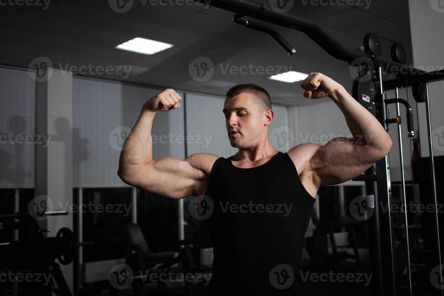 porträtt av ett idrottare, en sporter man tränare gör ett övning på simulator i de Gym. friska aktiva livsstil, skakningar muskler. stor muskulös vapen, biceps och triceps foto