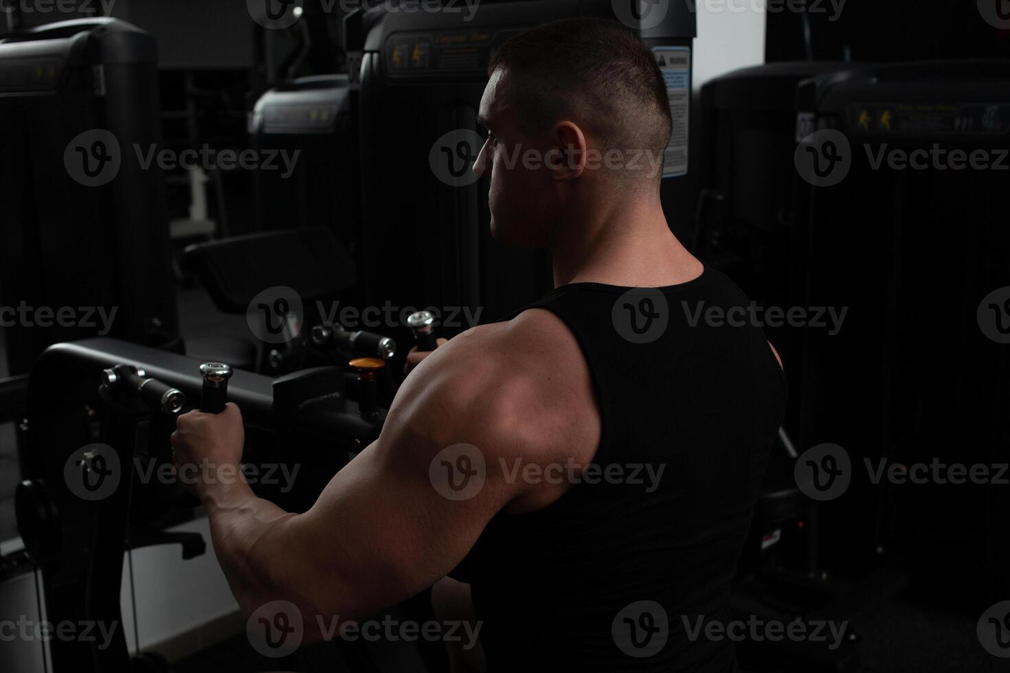 porträtt av en stilig manlig tränare i Gym. de idrottare gör ett övning på de simulator i de Gym. bygger muskel, spelar sporter, en friska livsstil. sitter foto