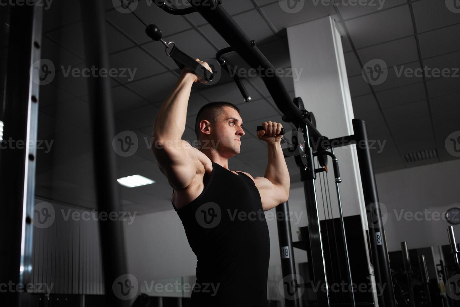 porträtt av ett idrottare, en sporter man tränare gör ett övning på simulator i de Gym. friska aktiva livsstil, skakningar muskler. sexuell foto