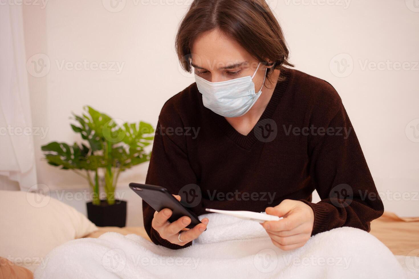 en sjuk man samtal ett ambulans på de telefon. en maskerad man checkar de temperatur och rattar de läkares siffra på de telefon. coronavirus, Hem karantän. foto