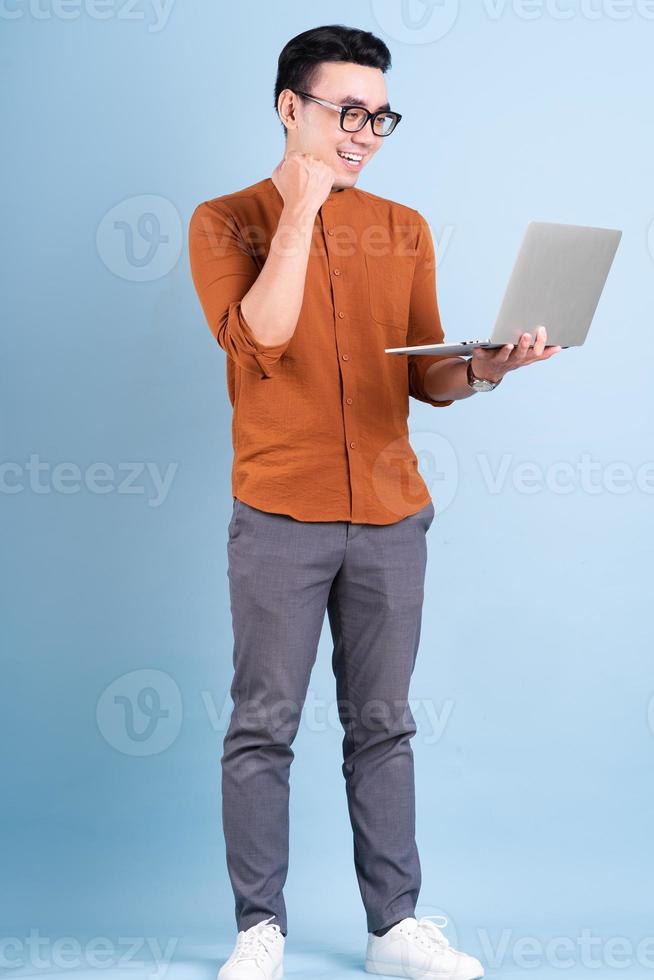 ung asiatisk affärsman som använder bärbar dator på blå bakgrund foto