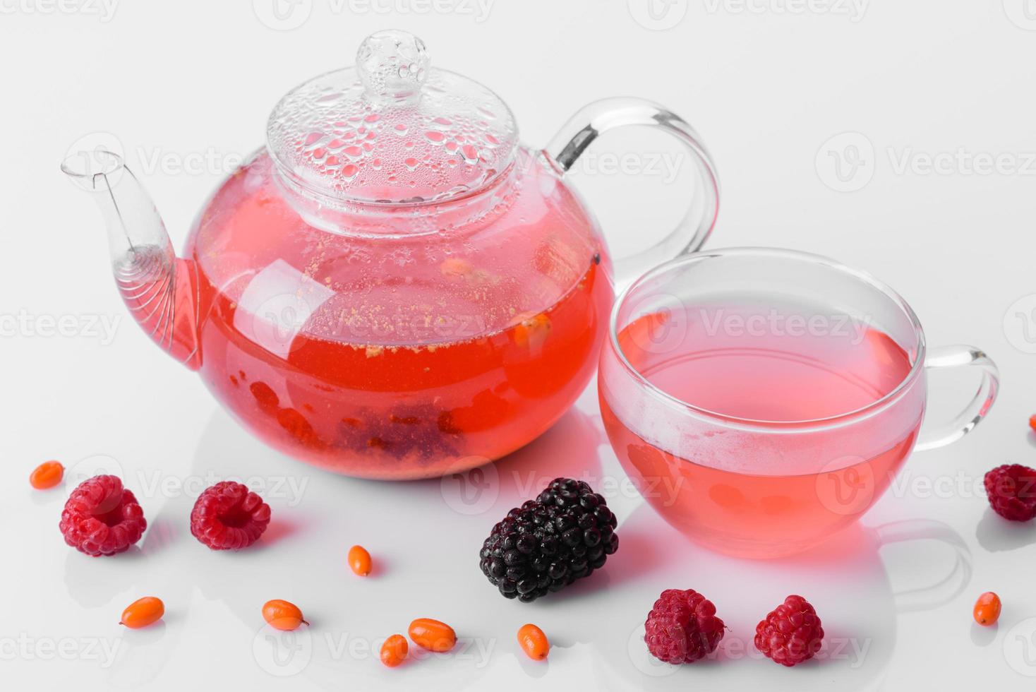 utsökt te av bär och frukter i en vacker glas tekanna på en vit bakgrund med reflektion foto