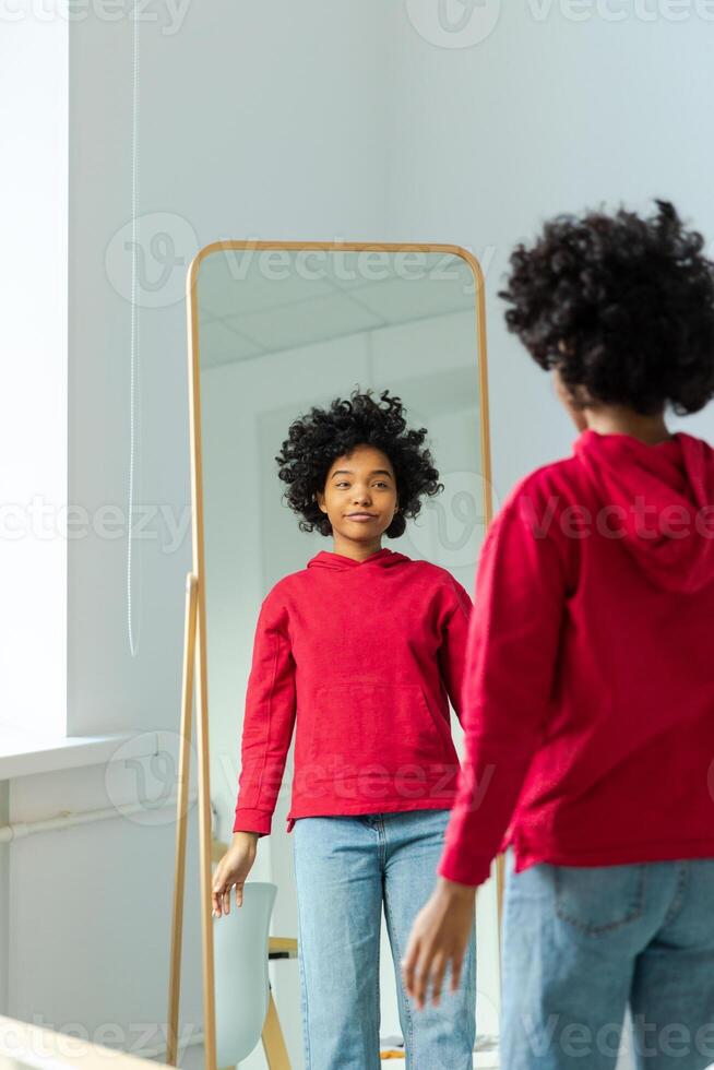 kärlek själv. skön ung leende afrikansk amerikan kvinna dans njuter henne spegel reflexion. svart lady ser på spegel ser självsäker och Lycklig. själv kärlek begrepp foto