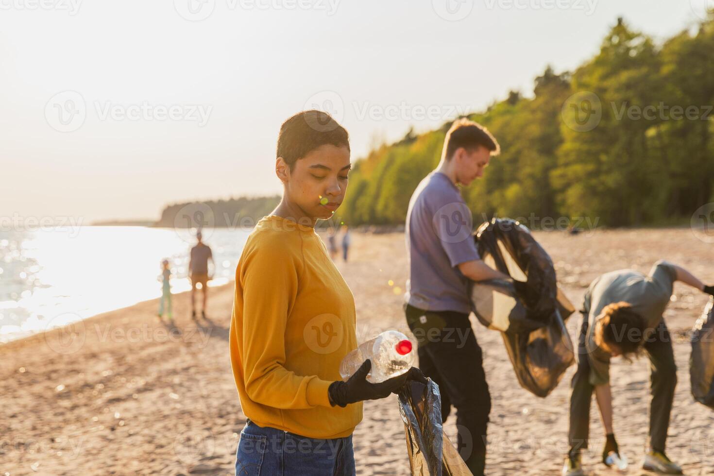 jord dag. volontärer aktivister team samlar sopor rengöring av strand kust zon. kvinna sätter plast flaska skräp i sopor väska på hav Strand. miljö- bevarande kust zon rengöring foto