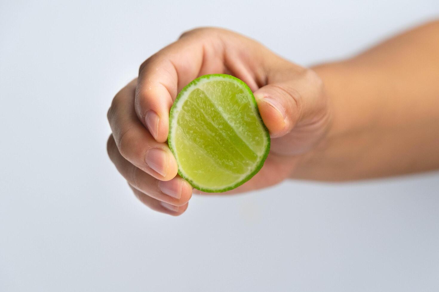 kvinna hand klämma halv färsk citron- isolerat på vit bakgrund. klämma färsk citron- stänga upp. höjd vitamin c naturlig foto