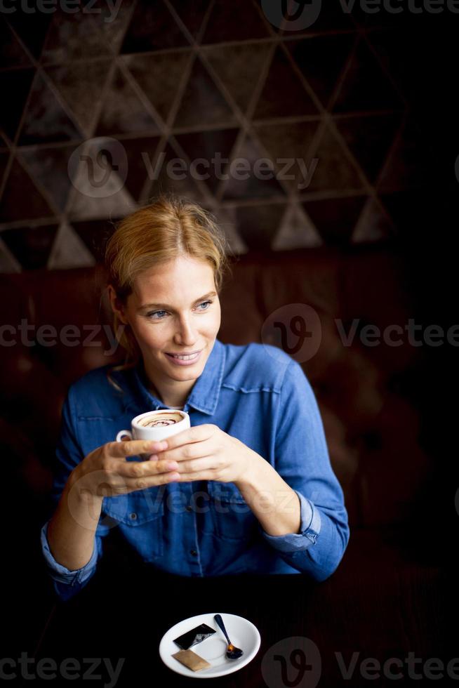 leende ung kvinna som dricker kaffe på café foto