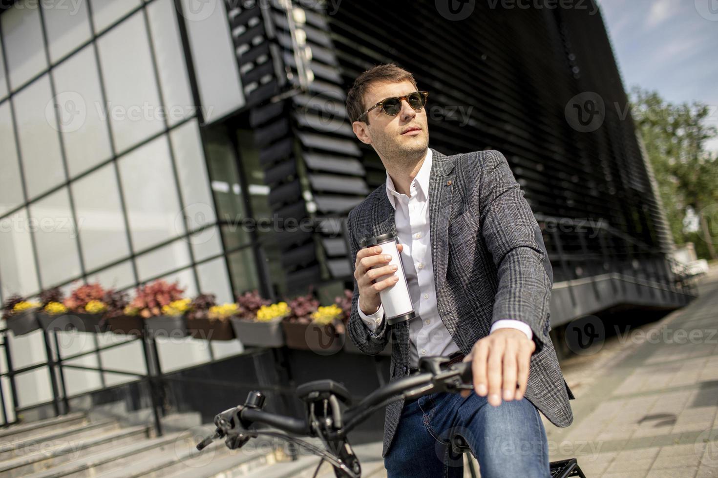 ung affärsman på elcykeln med takeaway kaffekopp foto