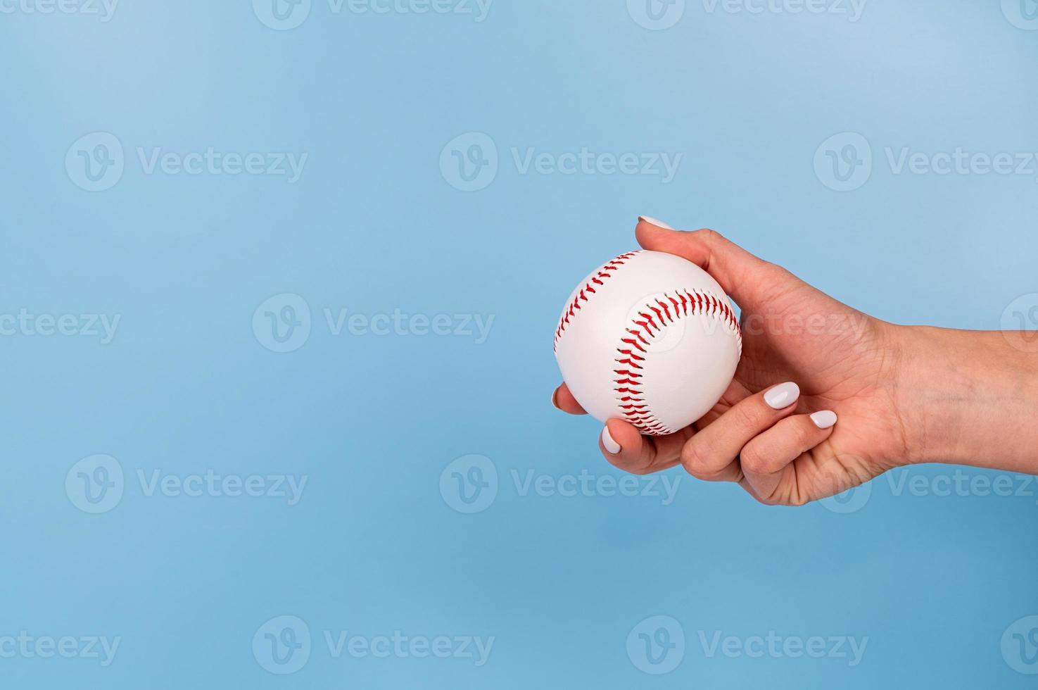 kvinnlig hand med vita naglar som håller vit baseball på blå bakgrund foto