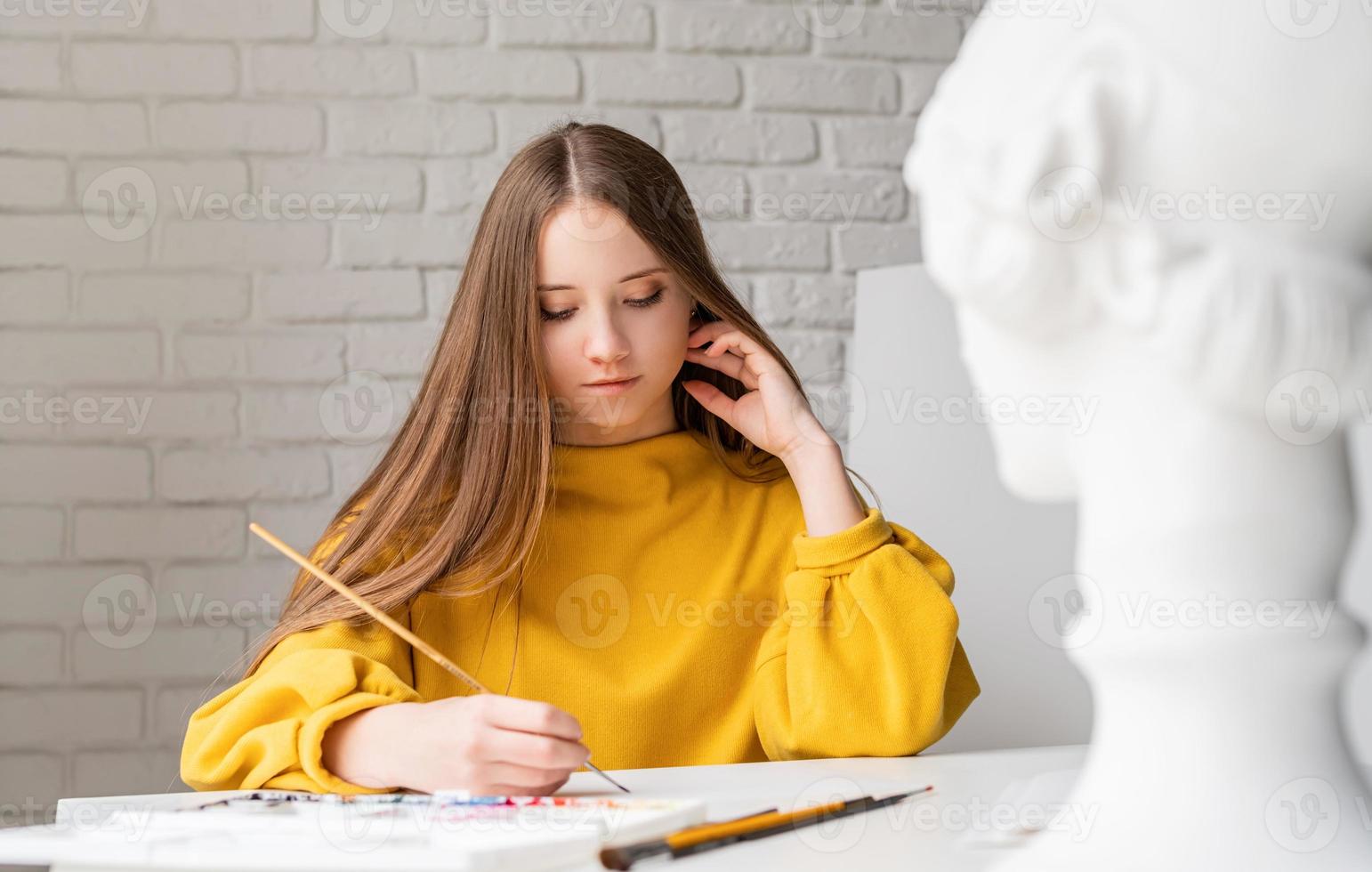 kvinnlig konstnär som målar en bild med akvarell i studion foto