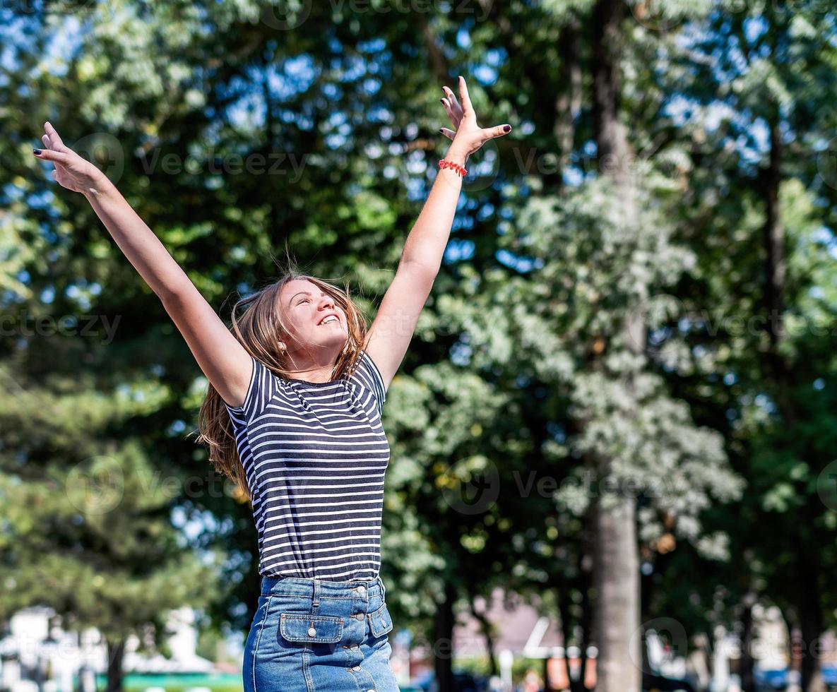 glad kaukasisk kvinna i avslappnade kläder leende och ha kul i parken på sommarsolig dag foto