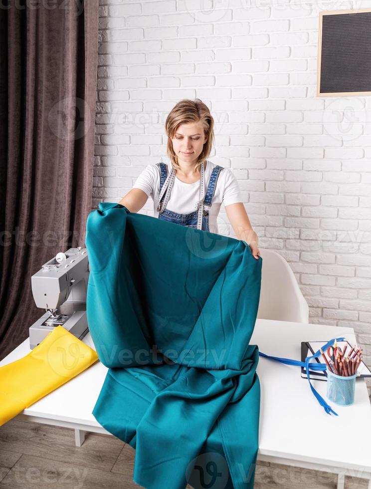 kvinnaskräddare som arbetar med textil i sin studio foto