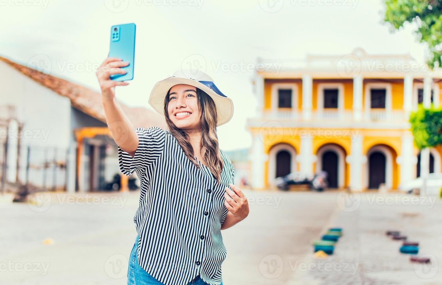 Lycklig turist flicka tar selfie i de katedral av granada. ung resa kvinna med hatt tar en selfie i en fyrkant foto