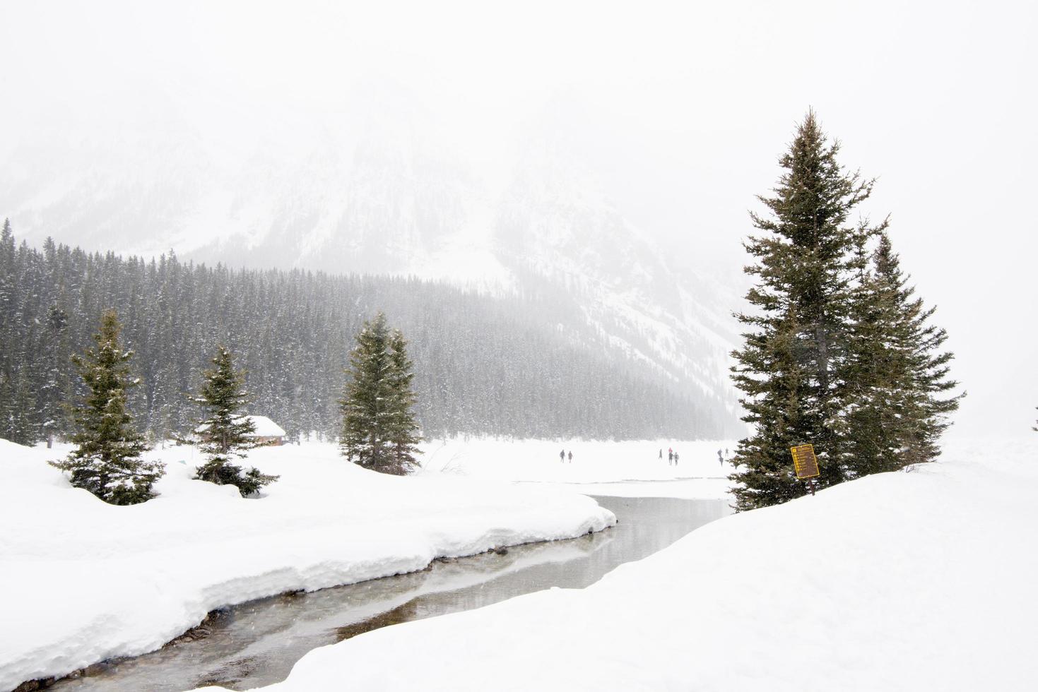 vackert vinterlandskap vid sjön luise, med frusen sjö, snöskog och människor i fjärran. Kanada. foto