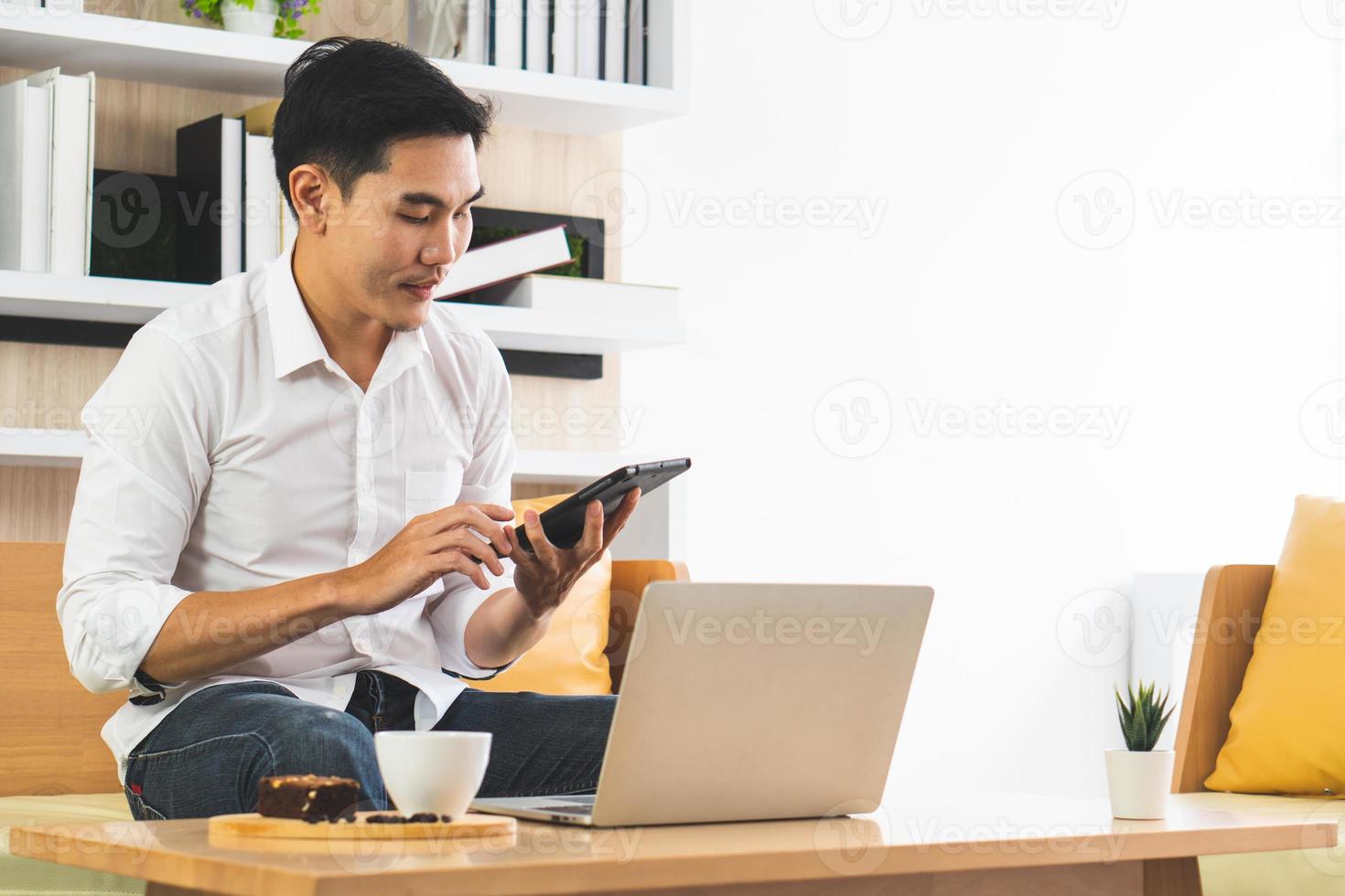 ung stilig asiatisk man som använder datorn för att arbeta hemifrån. affärs- och teknikkoncept foto