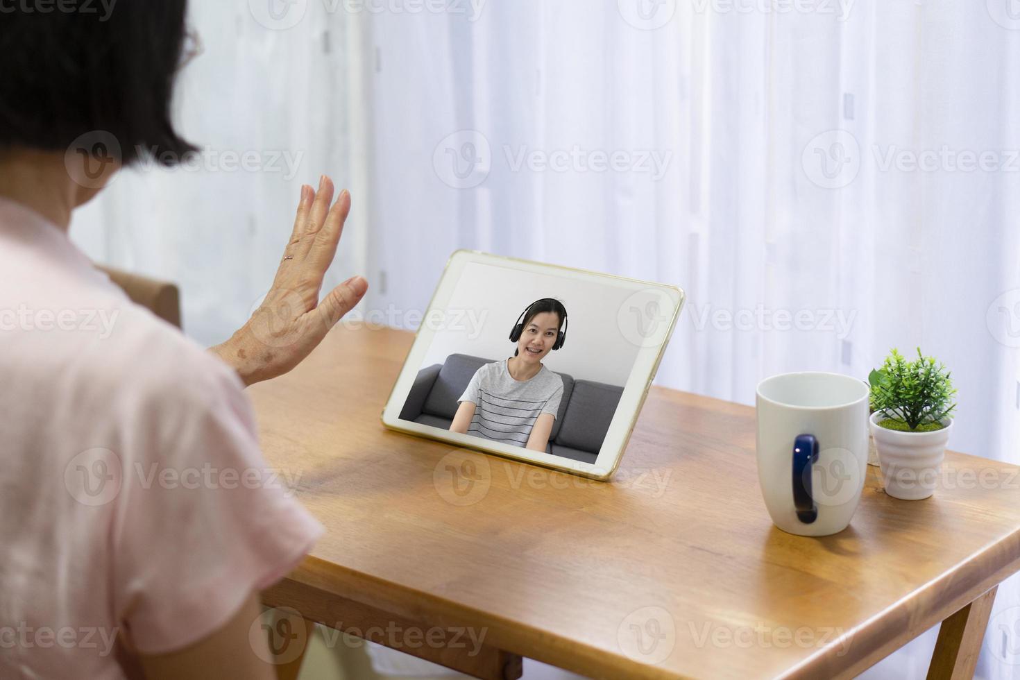 senior asiatisk kvinna som använder datorn för att videosamtala och prata med dottern hemifrån foto