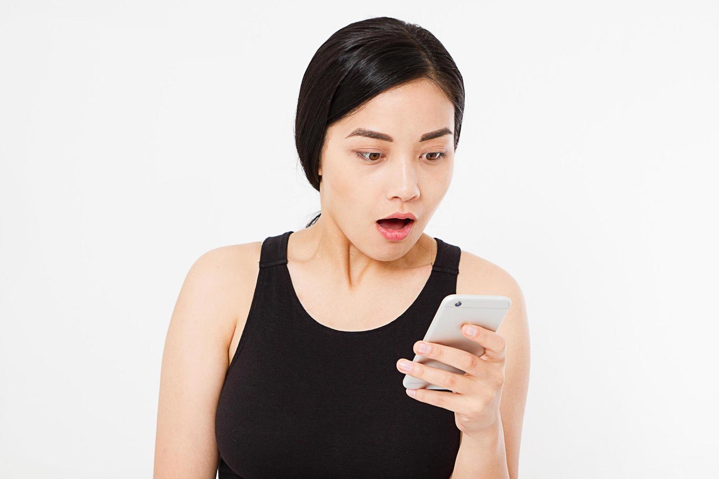 förvånad, sexig japansk, koreansk kvinna håller mobiltelefon isolerad på vit bakgrund, kopiera utrymme foto