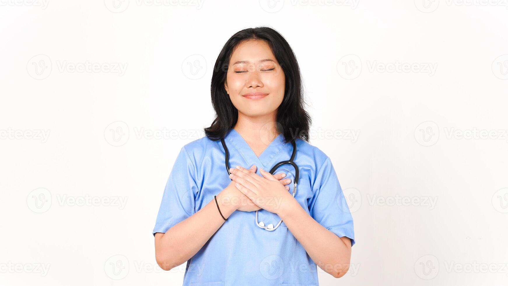 ung asiatisk kvinna läkare hand på bröst tacksam gest isolerat på vit bakgrund foto