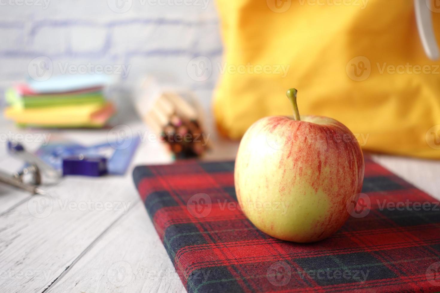 svart till skolakoncept med äpple på anteckningsblocket på bordet. foto
