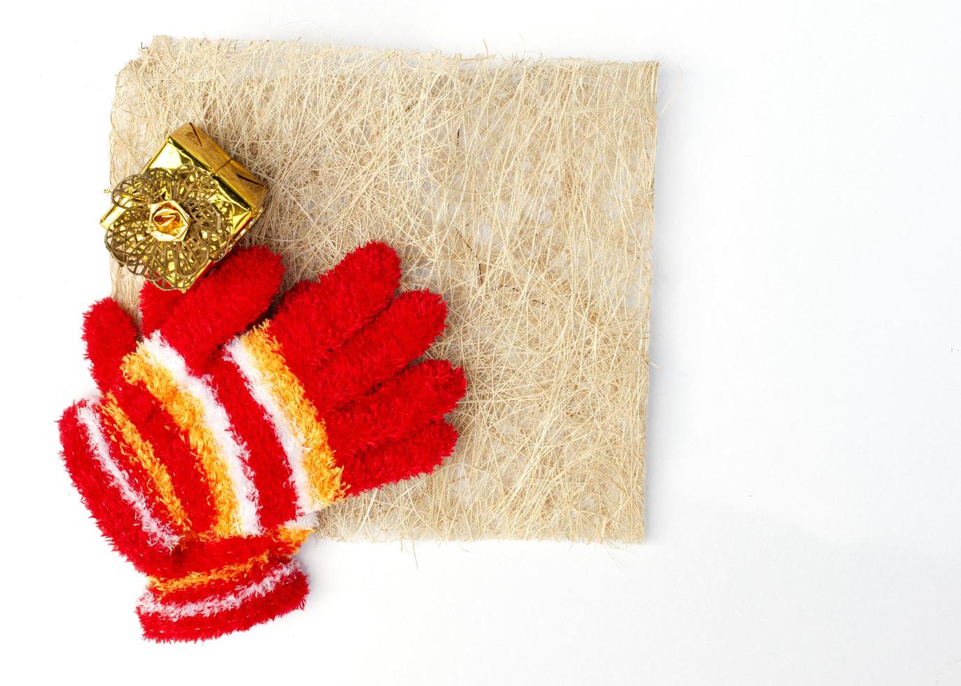 julstickade röda handskar och guldpresentask på vit bakgrund med plats för text foto