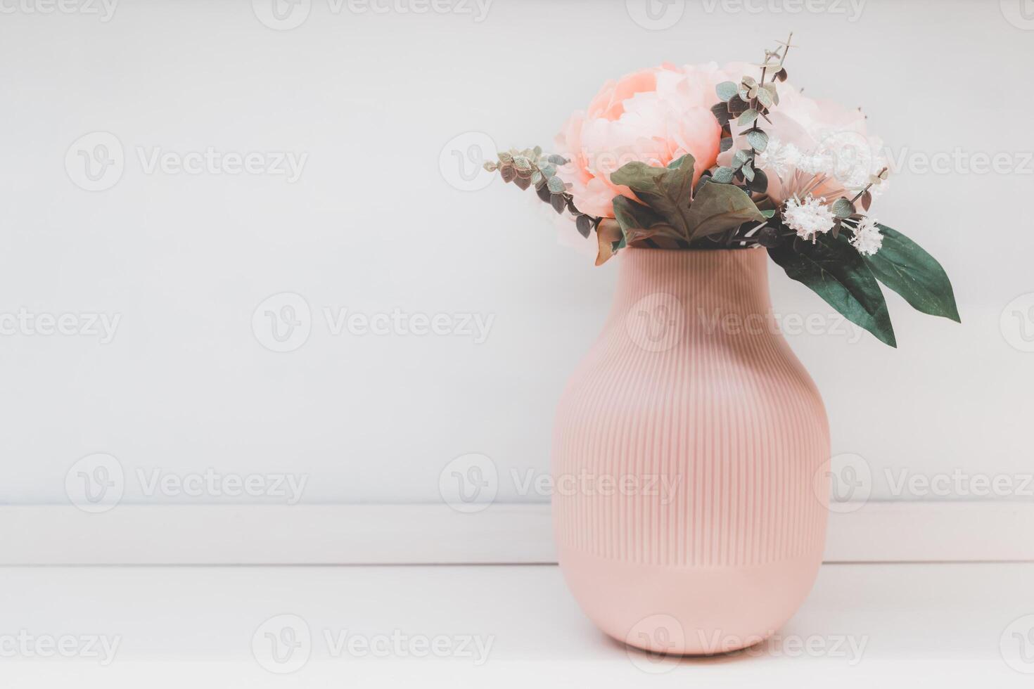 skön bukett av rosa blommor i en eleganta rosa vas på tabell mot vit bakgrund. Plats för text. foto