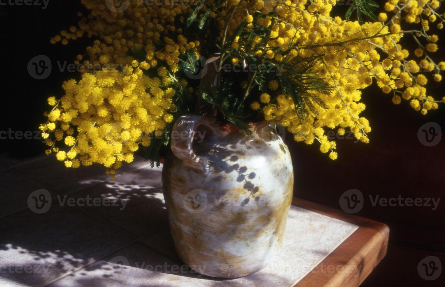 en vas fylld med gul blommor Sammanträde på en tabell foto