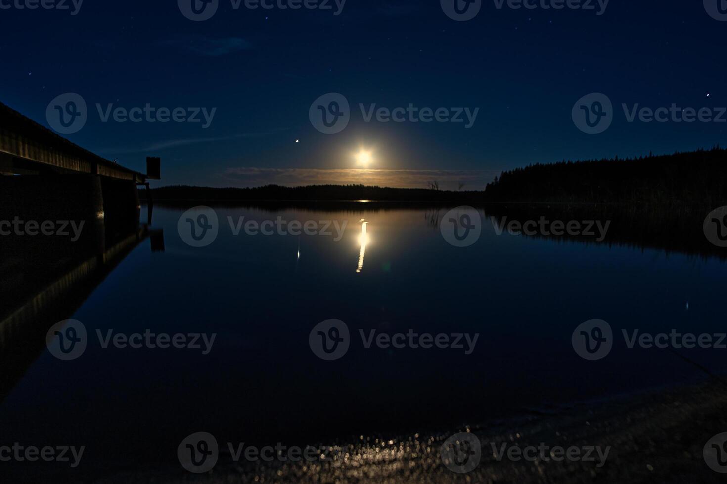 solnedgång på en sjö i Sverige. de månsken är reflekterad i de lugna vatten. foto