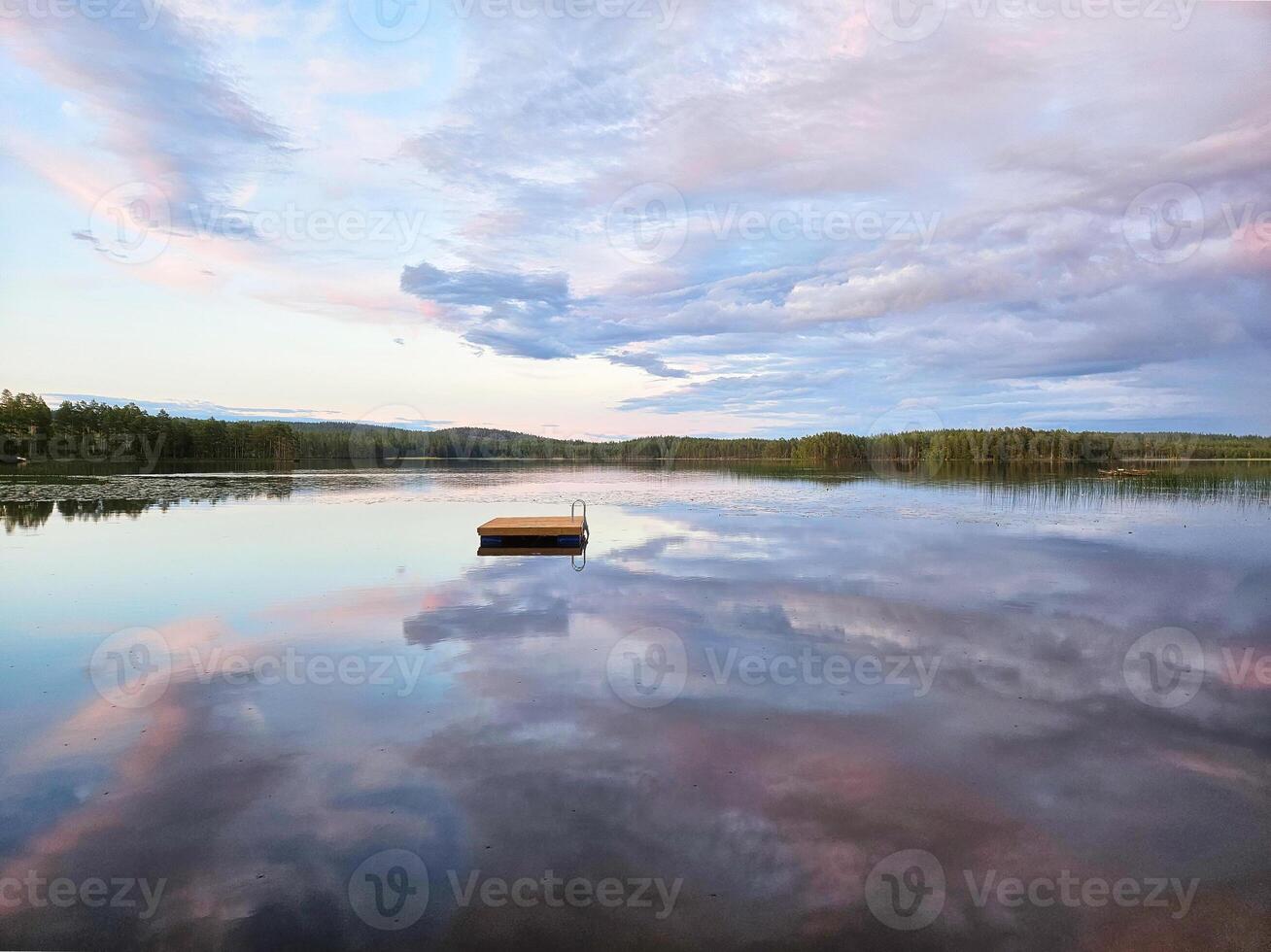 simning ö i Sverige på en sjö på solnedgång. moln reflekterad i de vatten. foto