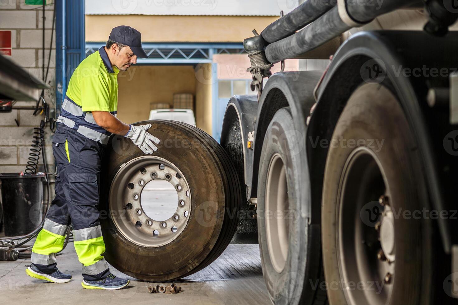 manlig mekaniker reparation lastbil hjul i verkstad foto