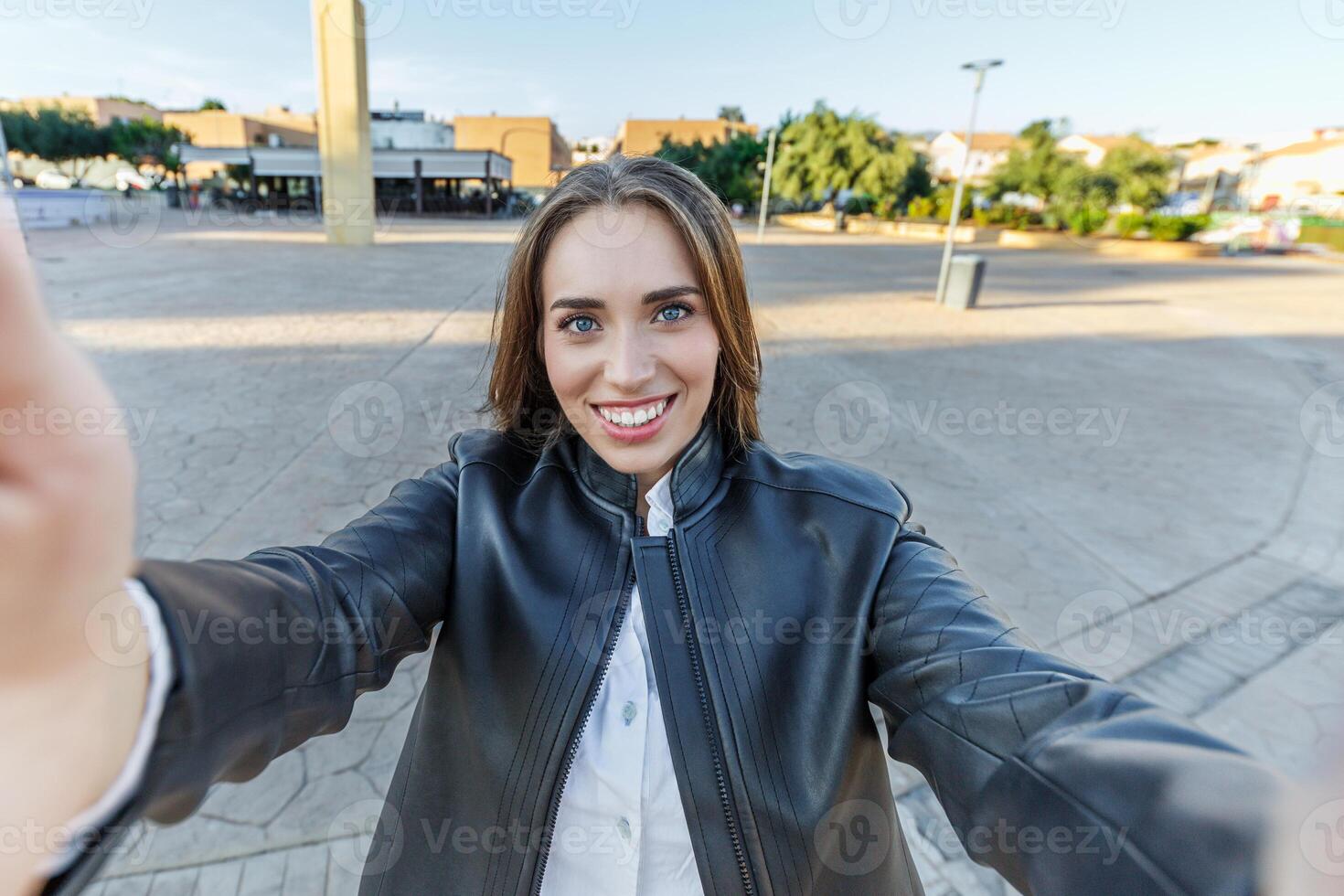 leende ung kvinna tar en selfie i de stad foto