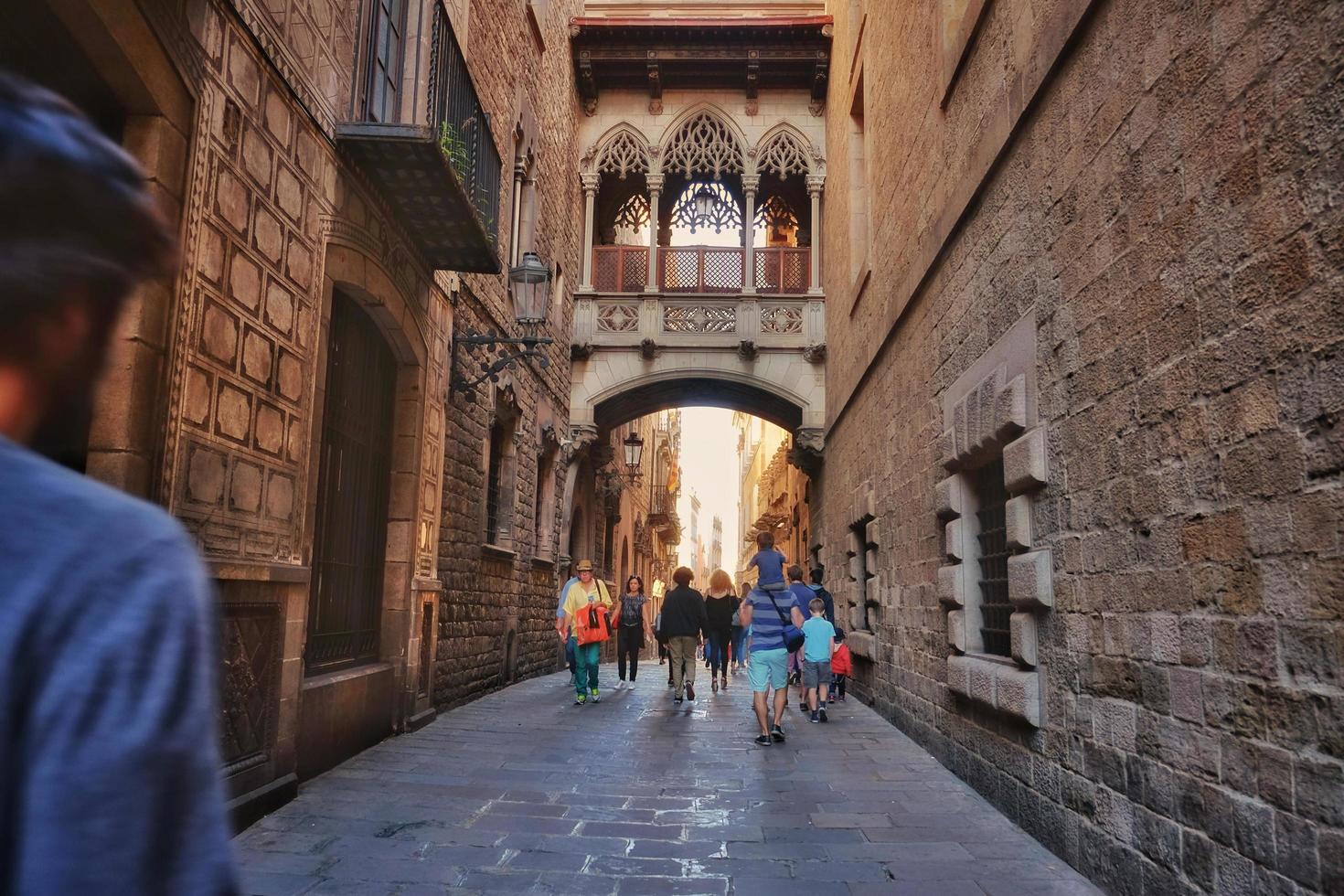 barcelona, spanien, 2017 - lokalbefolkningen och turisterna går på en smal gata nära den antika vintage neogotiska biskopsbron i carrer del bisbe. foto