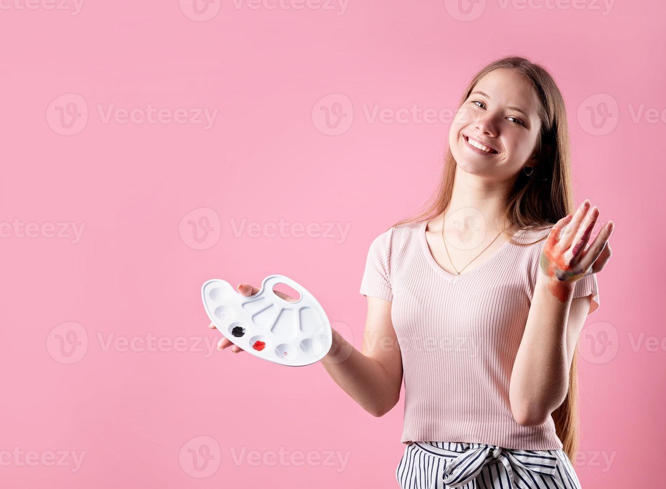 kvinnakonstnär med en färgpalett och penslar isolerade på rosa bakgrund foto