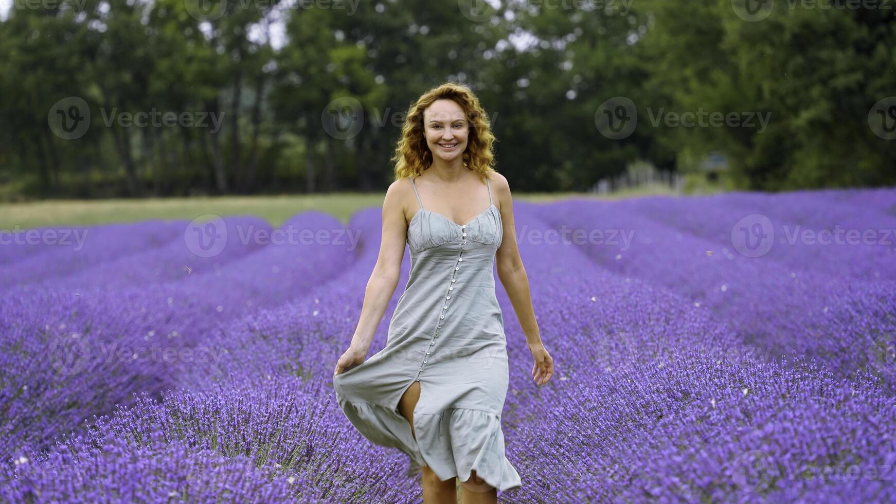 ung kvinna i en blå klänning gående genom lavendel- fält. handling. skön flicka i provence, Frankrike. foto