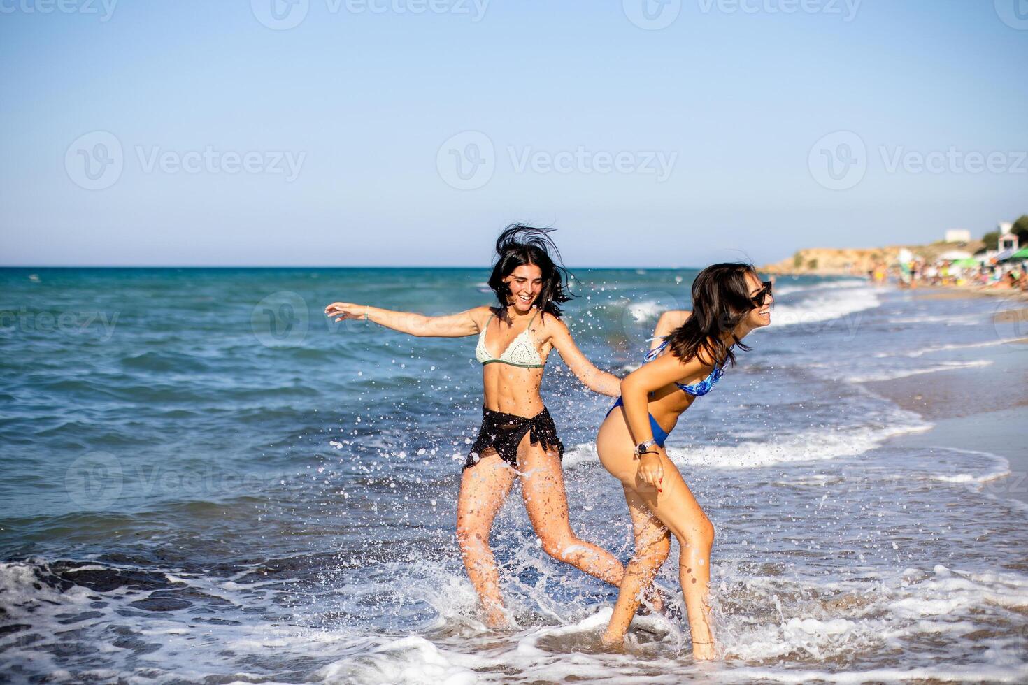 två Söt ung kvinna har roligt på de havet foto