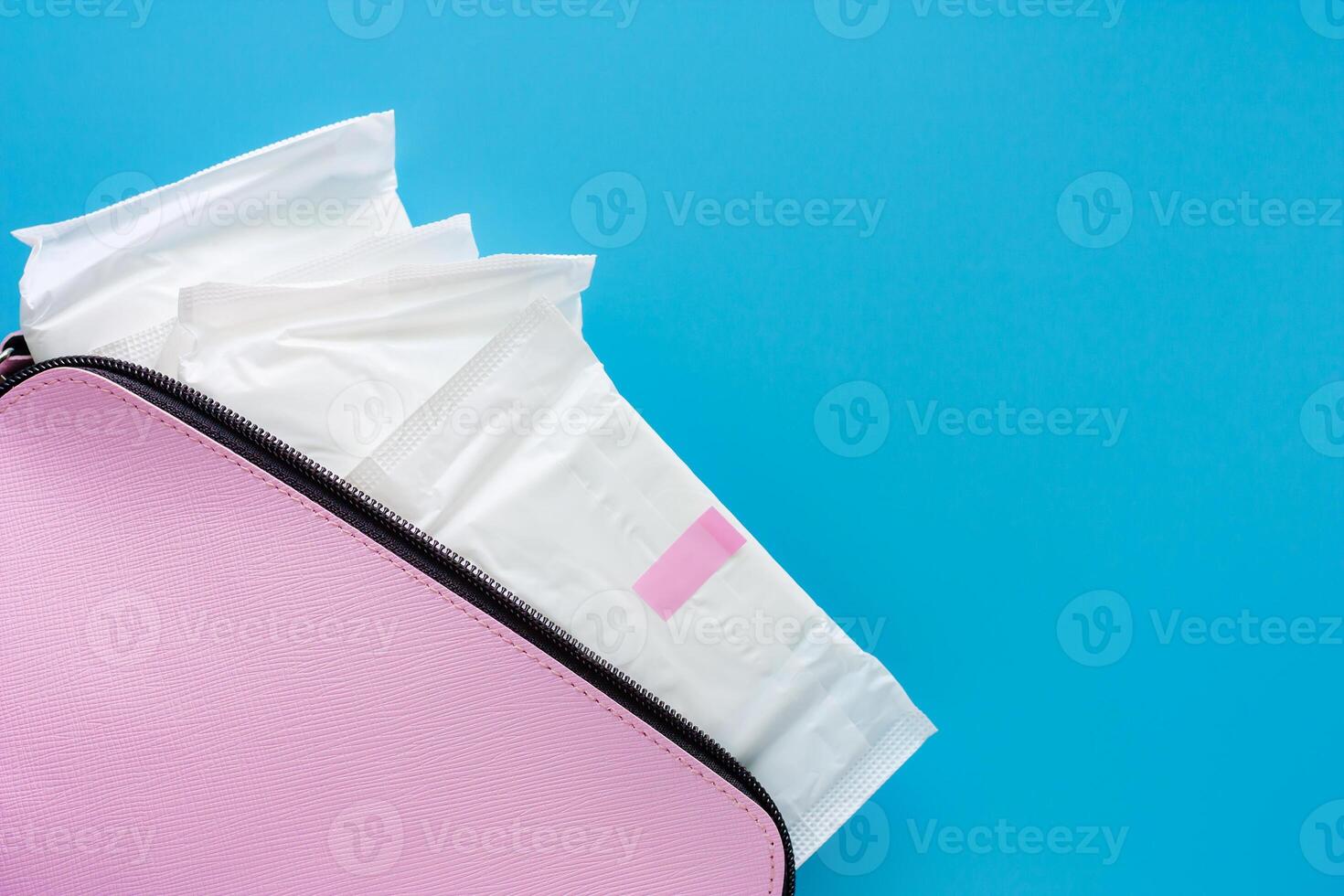 sanitär servett i kvinnors rosa väska på blå bakgrund foto