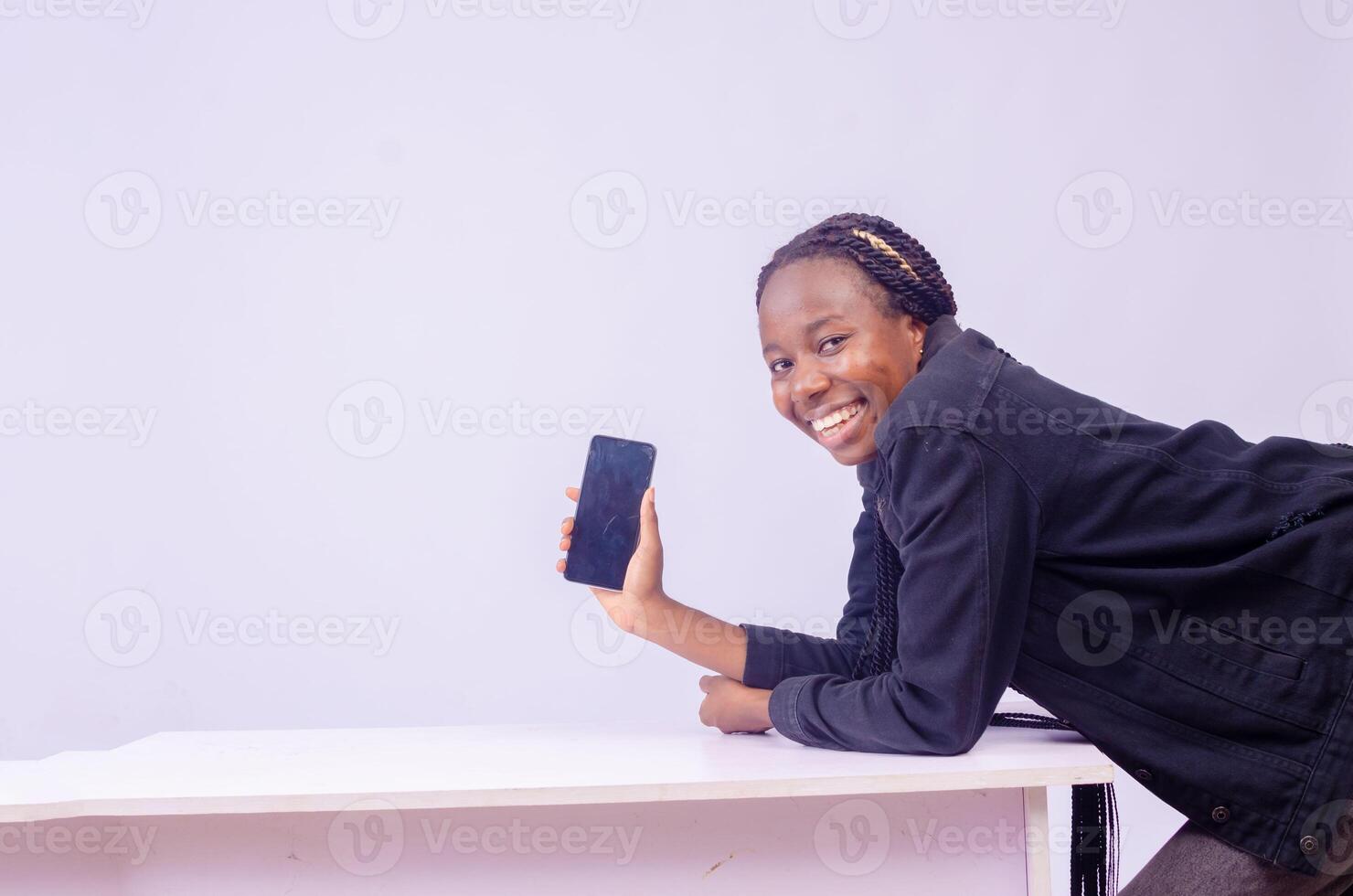 leende skön ung svart kvinna som visar henne telefon skärm foto