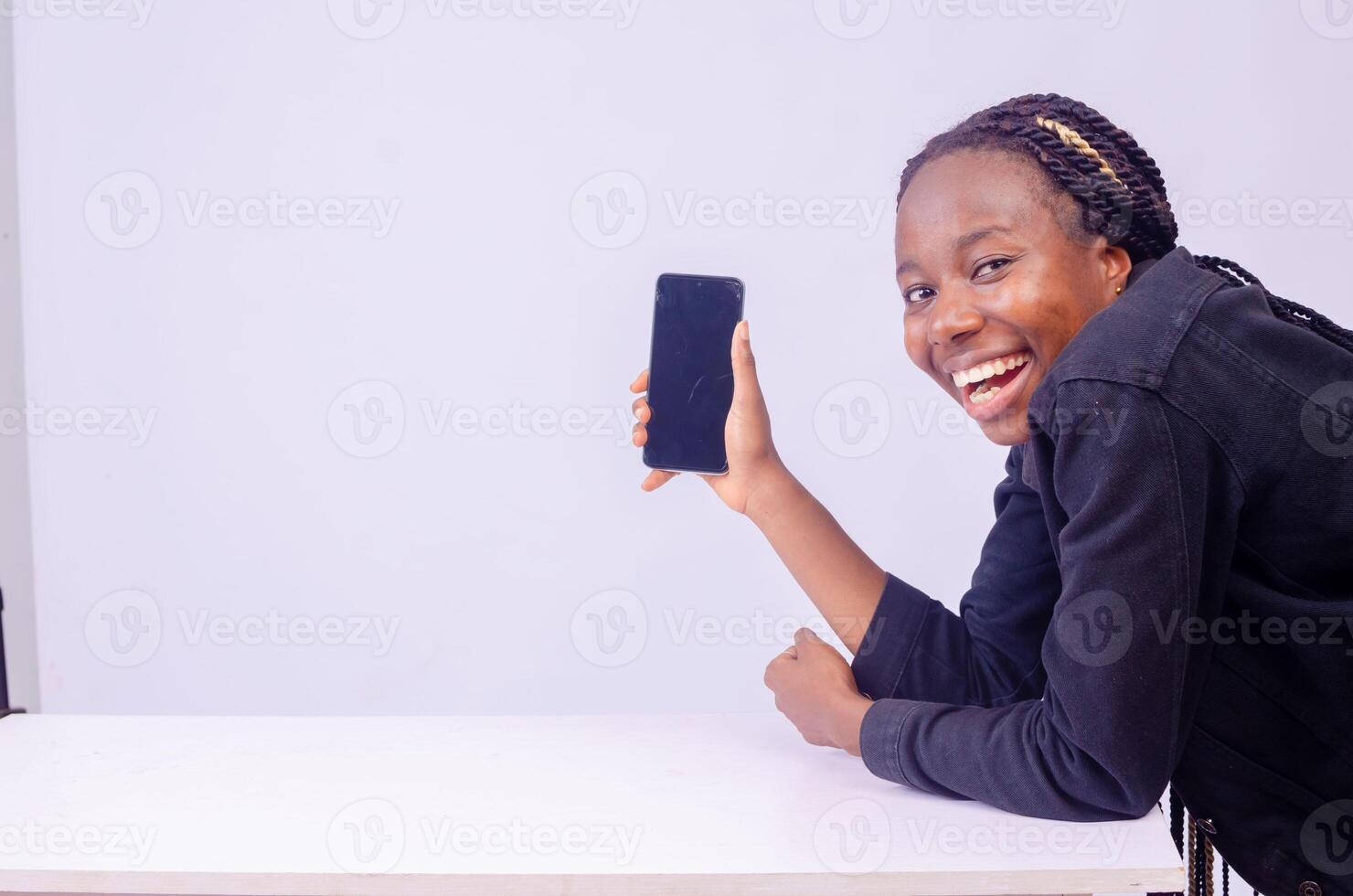 leende skön ung svart kvinna som visar henne telefon skärm foto