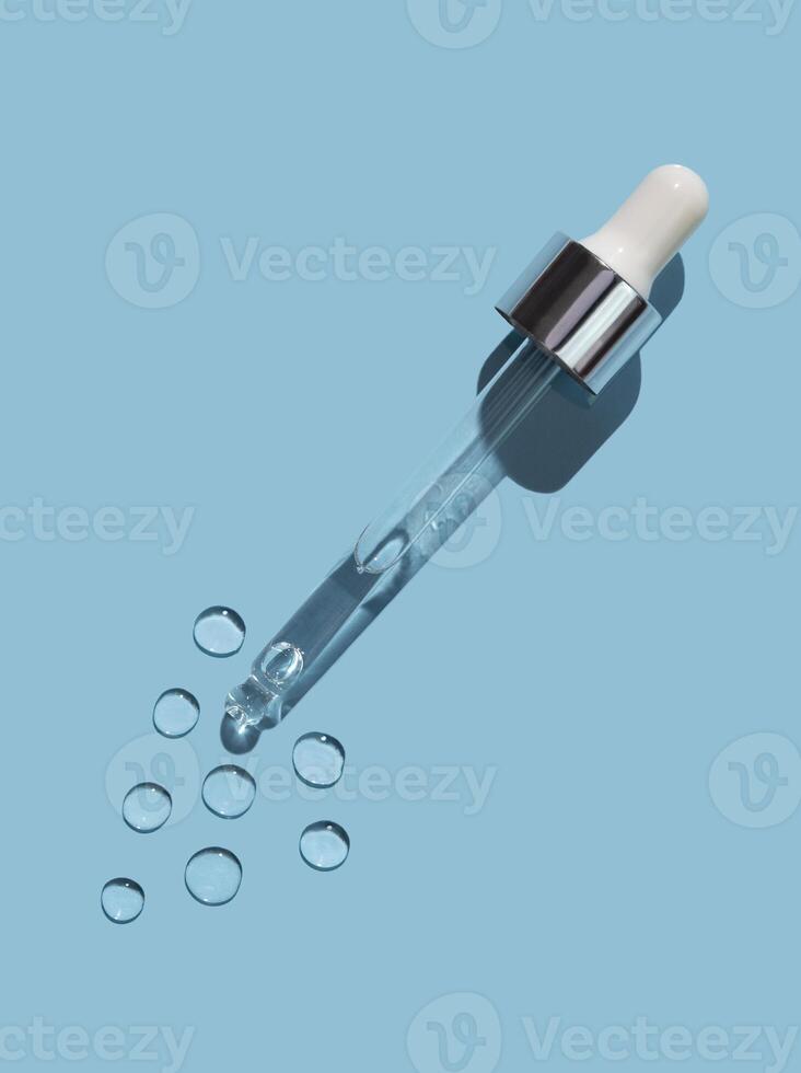 kosmetisk pipett med droppar av gel på en blå bakgrund. foto