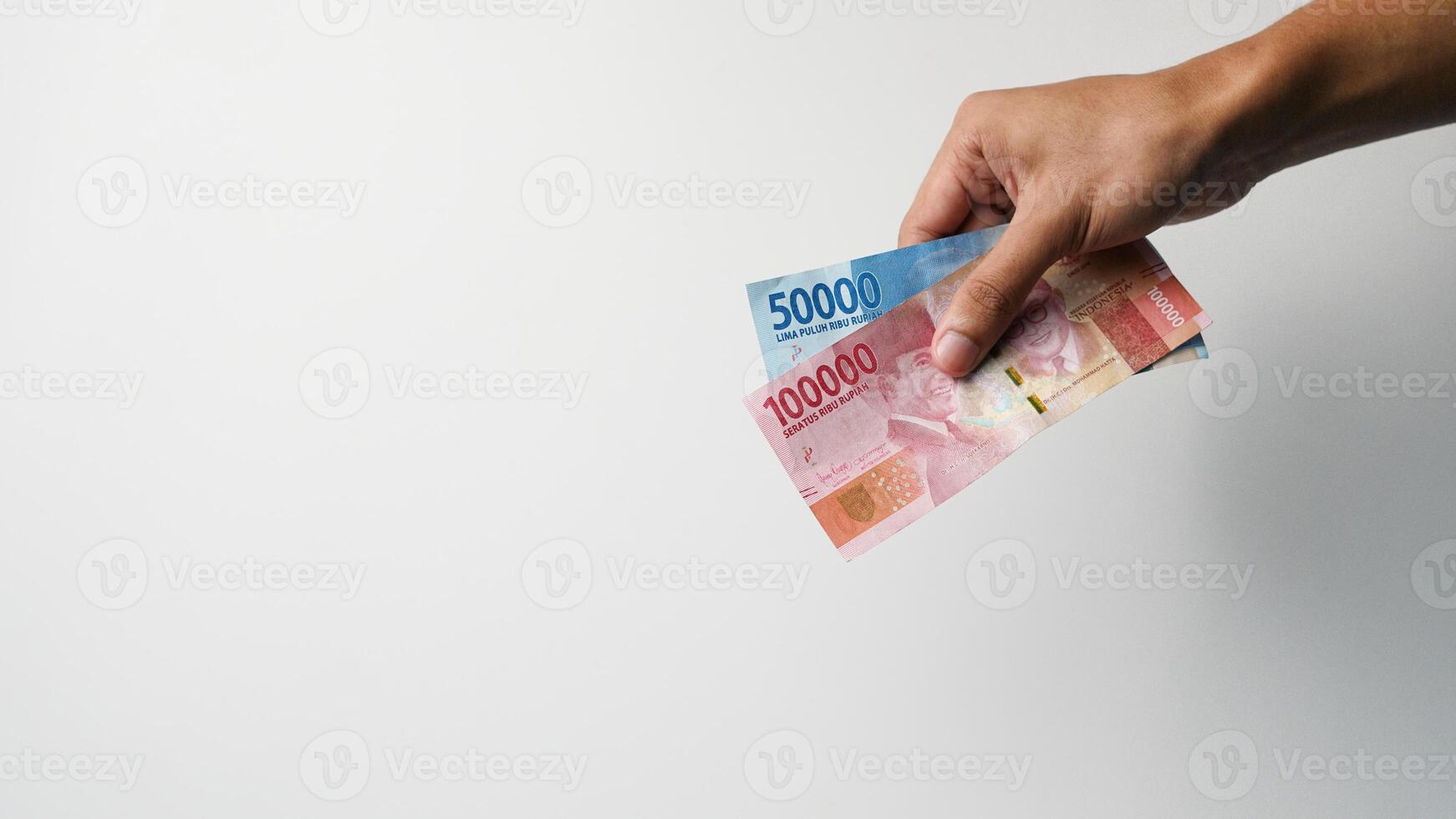 en mannens hand är innehav indonesiska pengar. begrepp av ger pengar foto