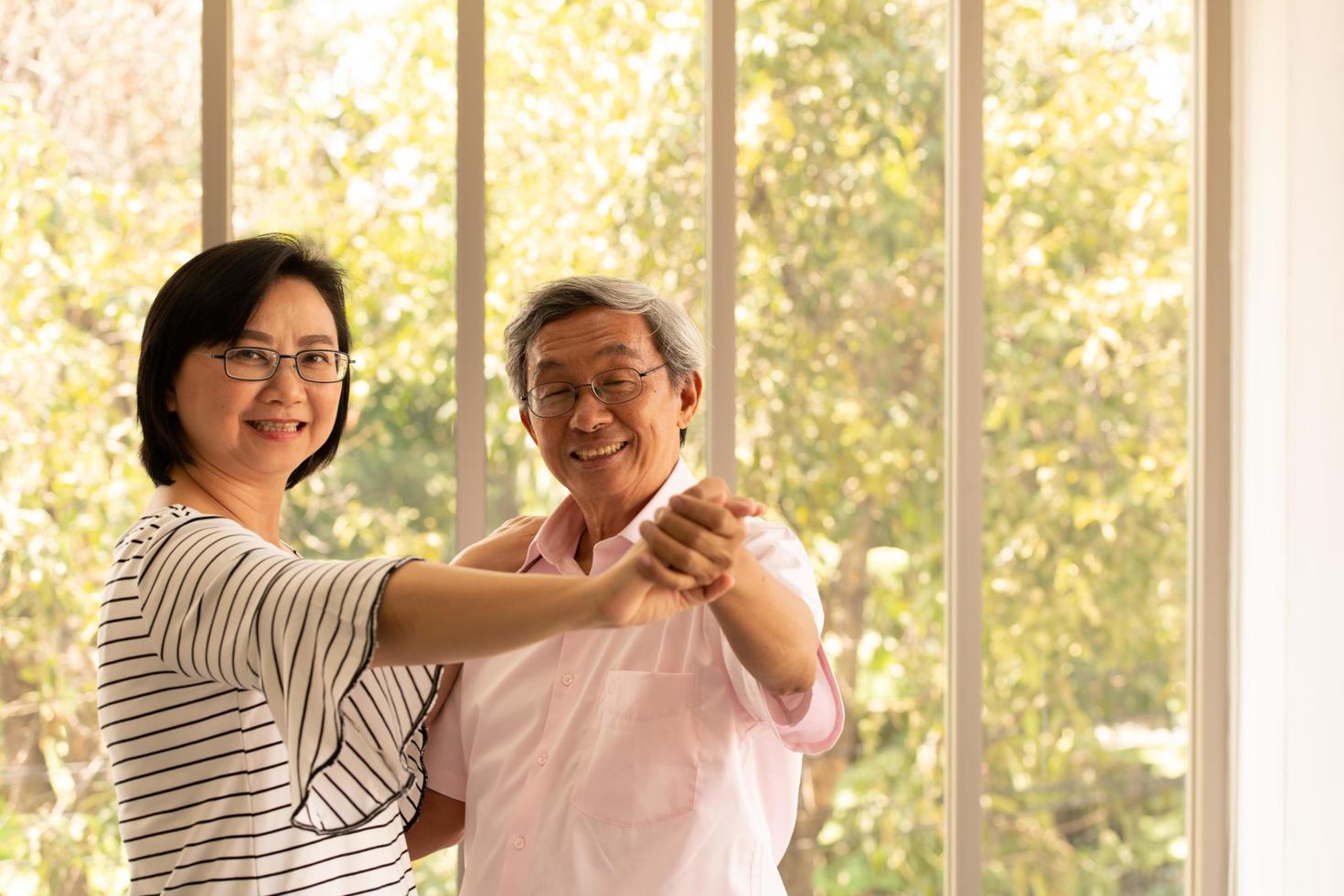 tillbringa tid tillsammans hemma ett äldre asiatiskt par som har kul att dansa i vardagsrummet foto