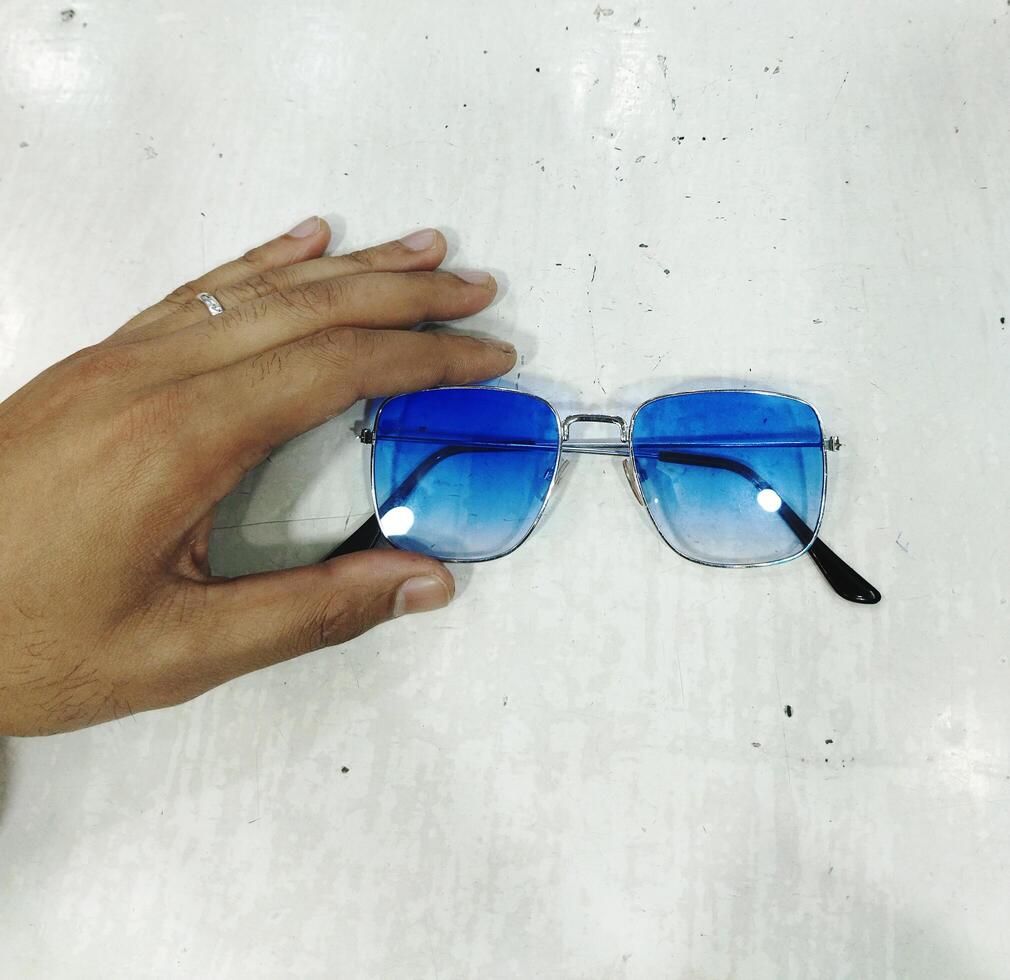 en person innehav upp en par av blå solglasögon foto